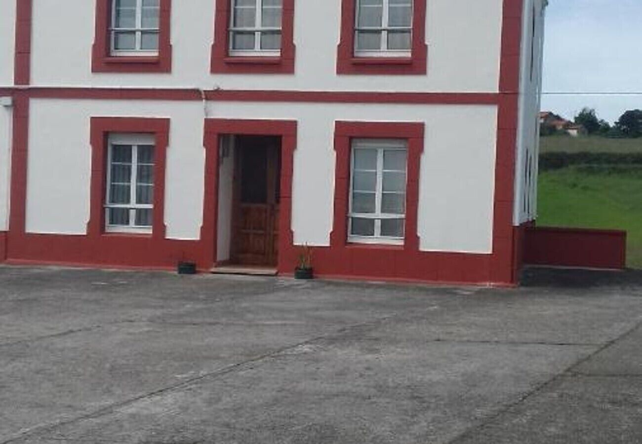 A two-story building with a red and white facade, a central entrance, and a paved ground.