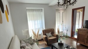Una sala de estar con sofá, sillón, mesa de centro y una lámpara blanca grande.