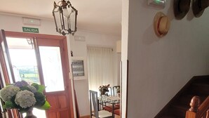 Un comedor con una silla de madera, una mesa y un jarrón de flores.