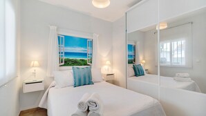 Een slaapkamer met een bed, twee nachtkastjes, een raam met uitzicht en een spiegel.