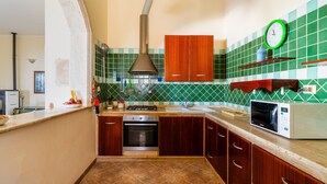 Een keuken met een fornuis, oven, magnetron en een klok aan de muur.
