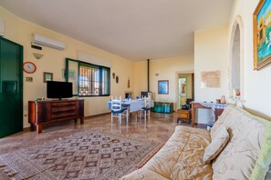 Ein Wohnzimmer mit einer Couch, einem Fernseher, einem Esstisch und einem gemusterten Teppich.