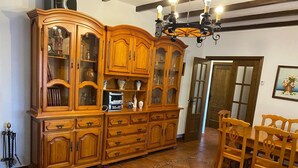 Un coin repas avec des meubles en bois, un buffet aux portes vitrées et un lustre.