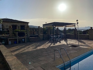 Un patio con piscina, mobiliario exterior y vistas a las montañas.