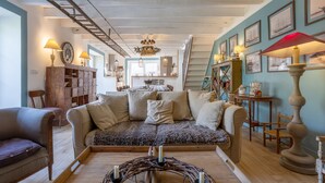Una sala de estar acogedora con un sofá, una mesa de centro con velas y una escalera que lleva a otra habitación.