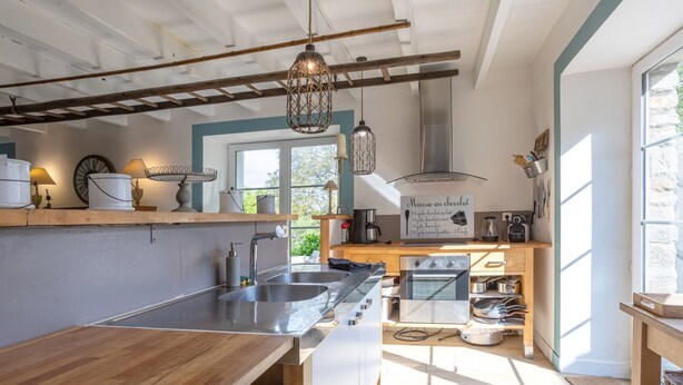 Una cocina moderna con encimera de madera, pileta de acero inoxidable y lámparas colgantes.