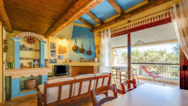 Ein gemütlicher Essbereich mit einer Holzbank und einem Tisch, einem Kamin aus Backsteinen und einem Balkon mit Blick.