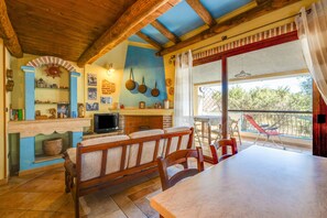 A cozy dining area with a wooden bench and table, a brick fireplace, and a balcony with a view.