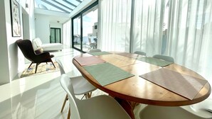 Uma área de jantar moderna com uma mesa grande, cadeiras e vista através de grandes janelas.