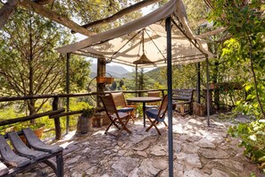 A rustic outdoor seating area with stone flooring, wooden furniture, and a canopy. - Villa 'Orgoai' with Mountain View, Wi-Fi and Air Conditioning (Orgosolo)