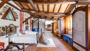 A rustic room with a bed, a large vase, and a wooden wardrobe.
