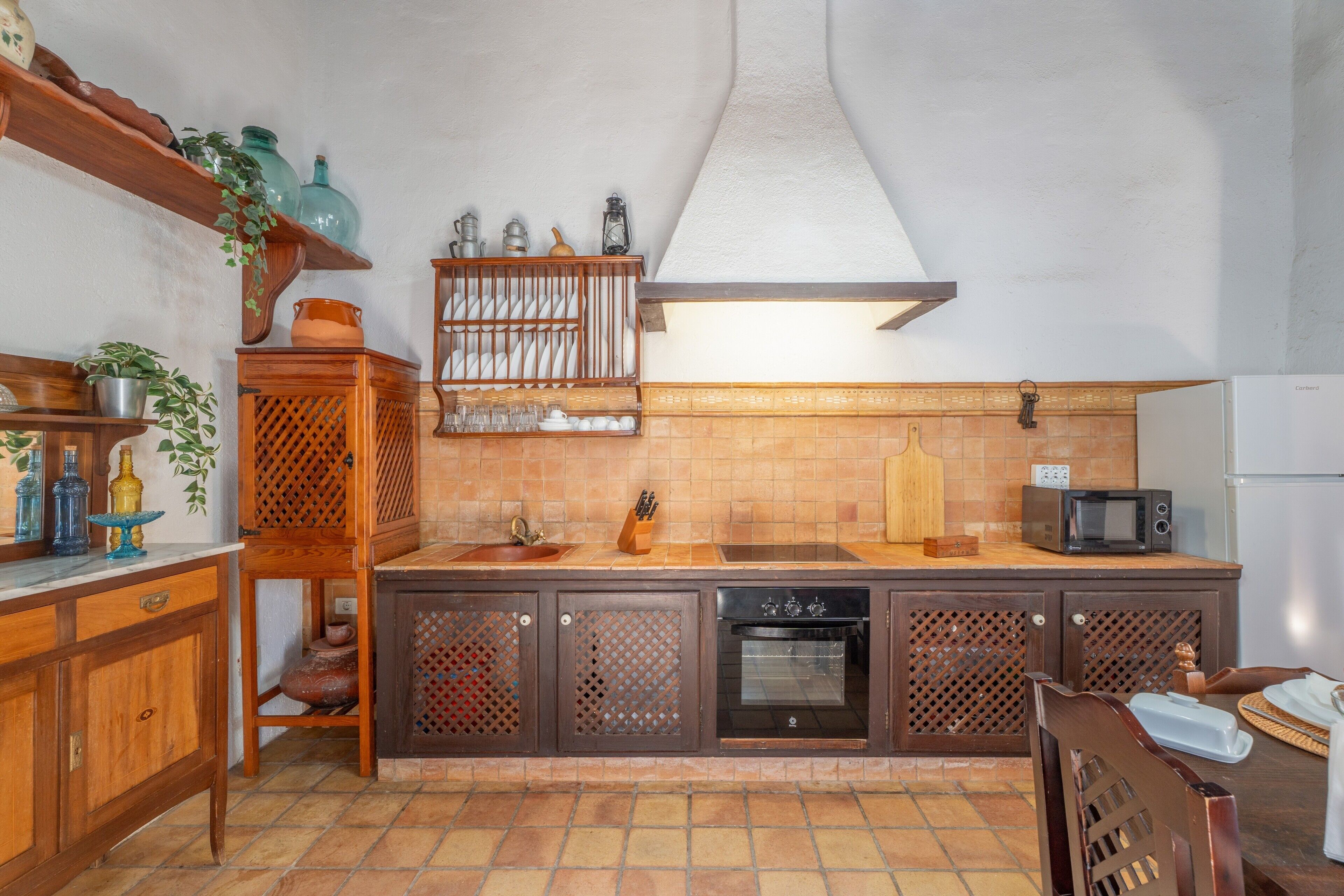 Een keuken met houten kastjes, een spoelbak, een fornuis en een magnetron.