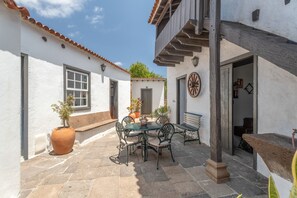 A courtyard with a table and chairs, potted plants, and a wooden bench. - Casa Rural La Tunera. Historic Canarian Home (1797), Sea & Mountain Views, Pool, Wi-Fi (Villa de Arico)