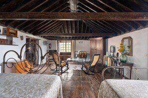 Ein rustikales Zimmer mit Holzbalken, zwei Schaukelstühlen, einem Tisch mit Stühlen und einem Bett.