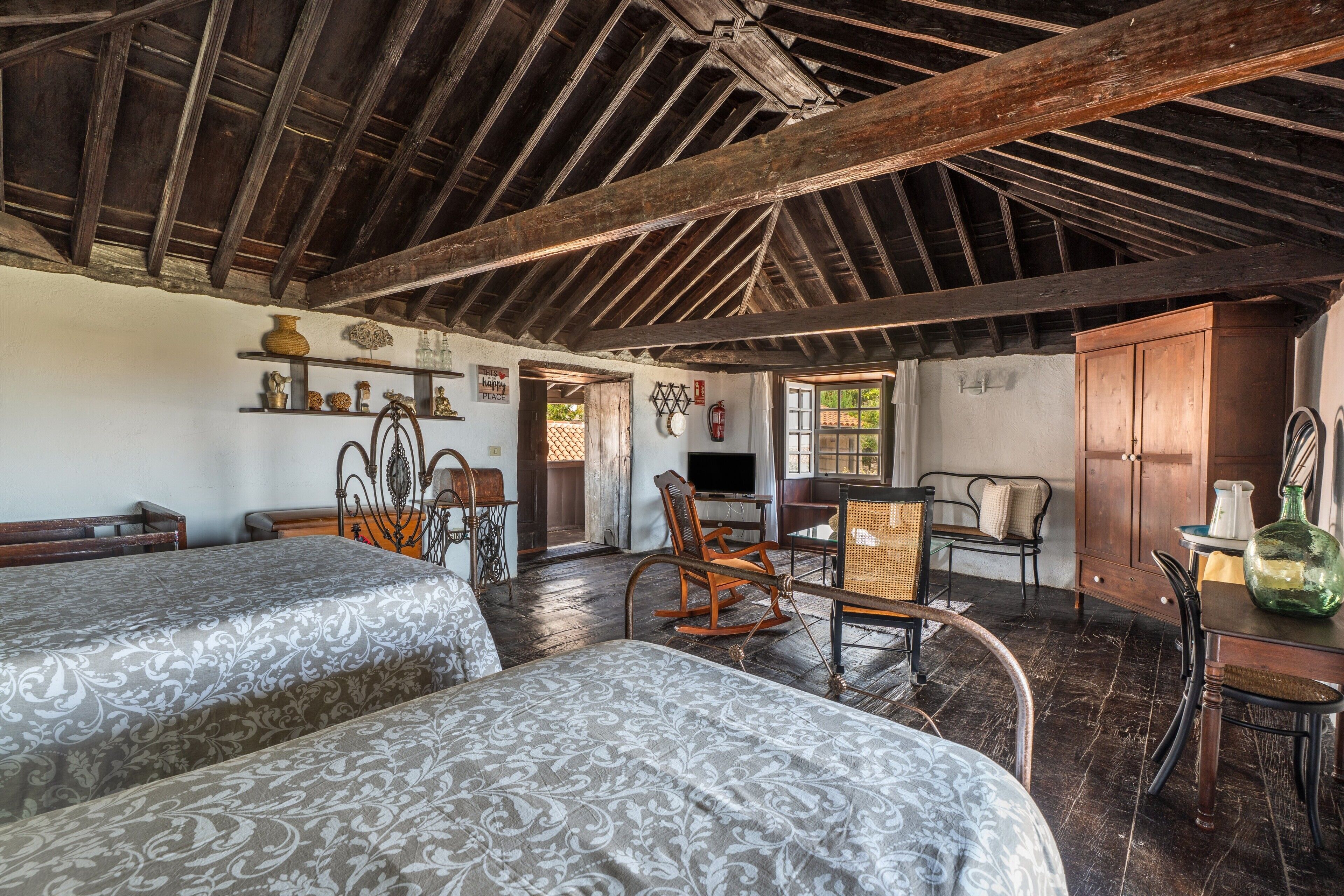 A rustic room with two beds, wooden furniture, a television, and a window with a view.