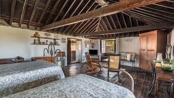 A rustic room with two beds, wooden furniture, a television, and a window with a view.
