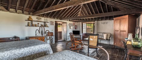 A rustic room with two beds, wooden furniture, a television, and a window with a view.