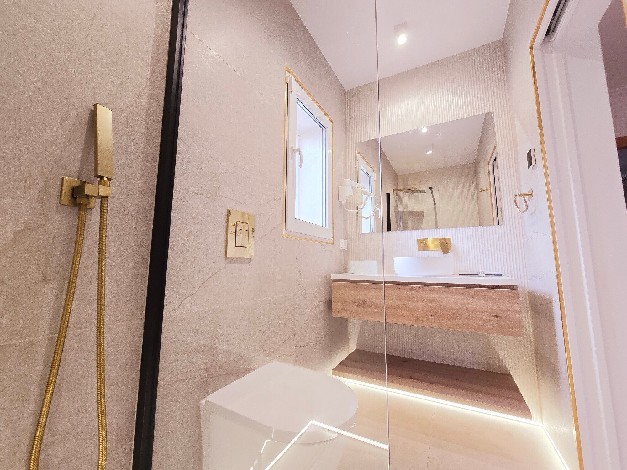 Un baño moderno con cabina de ducha de vidrio, tocador de madera y un espejo grande.