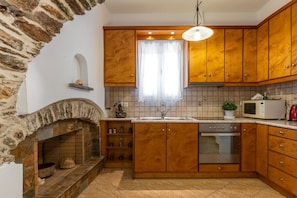 A kitchen with wooden cabinets, a built-in oven, a microwave, and a stone fireplace.
