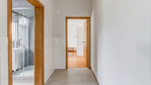 Un couloir avec une douche en verre, des portes en bois et un sol carrelé.