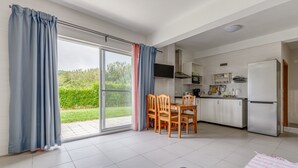 Une cuisine moderne avec un coin repas, de grandes portes-fenêtres coulissantes et un téléviseur à écran plat.