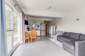 Un espacio habitable moderno con comedor, cocina y un sofá gris.