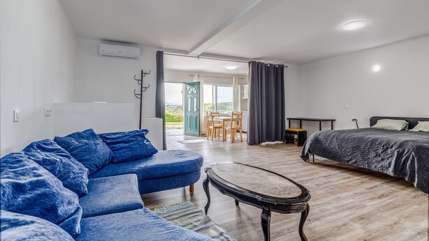 A modern room with a sofa, a bed, a small table, and a view of the outdoors. - Apartment 'Apartamento T2 Praia Do Almoxarife' with Sea View, Wi-Fi and Air Conditioning (Horta)
