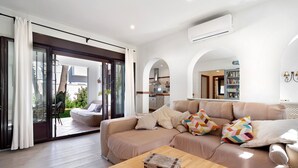 Een moderne woonkamer met een beige bank, een houten salontafel en een schuifdeur naar een terras.