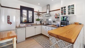 Een moderne keuken met witte kastjes, een houten aanrechtblad, een rvs afzuigkap en een magnetron.