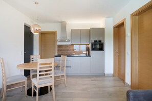 Une cuisine moderne avec un coin repas, des meubles en bois et un four encastré.