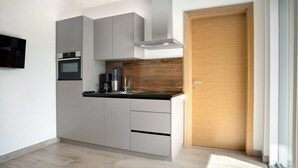 Una cocina moderna con electrodomésticos integrados, un revestimiento de pared de madera y un ventanal corredero.