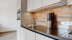 Een moderne keuken met een roestvrijstalen afzuigkap, een inbouwspoelbak en een houten achterwand.