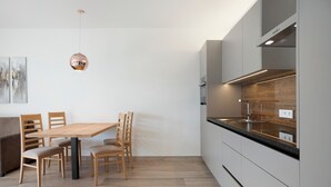Una cocina moderna con una mesa de comedor de madera, sillas y una lámpara colgante.