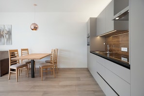 Una cocina moderna con una mesa de comedor de madera, sillas y una lámpara colgante.