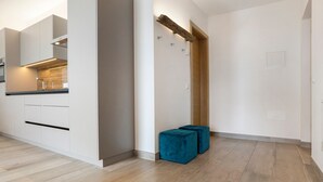 Una cocina moderna con electrodomésticos integrados, un revestimiento de pared de madera y un par de otomanas azules.