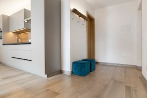 Una cocina moderna con electrodomésticos integrados, un revestimiento de pared de madera y un par de otomanas azules.