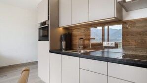 Eine moderne Küche mit Einbauofen, Spüle aus Edelstahl und einer Holzrückwand.