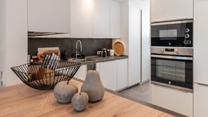 Cozinha moderna com armários brancos, forno preto e bancada de madeira.