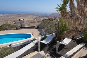 A pool with a view of the ocean, a hammock, and a chair. - 'Finca La Calerita C' with Sea View (Yaiza)