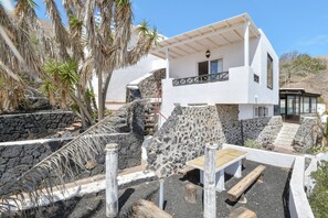 Un edificio moderno blanco con una escalera de piedra, una mesa de madera y un banco.