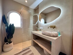 A modern bathroom with a glass shower enclosure, a round mirror, a marble sink, and a potted plant. - Villa 'Nono' with Amazing Sea View (Altea)