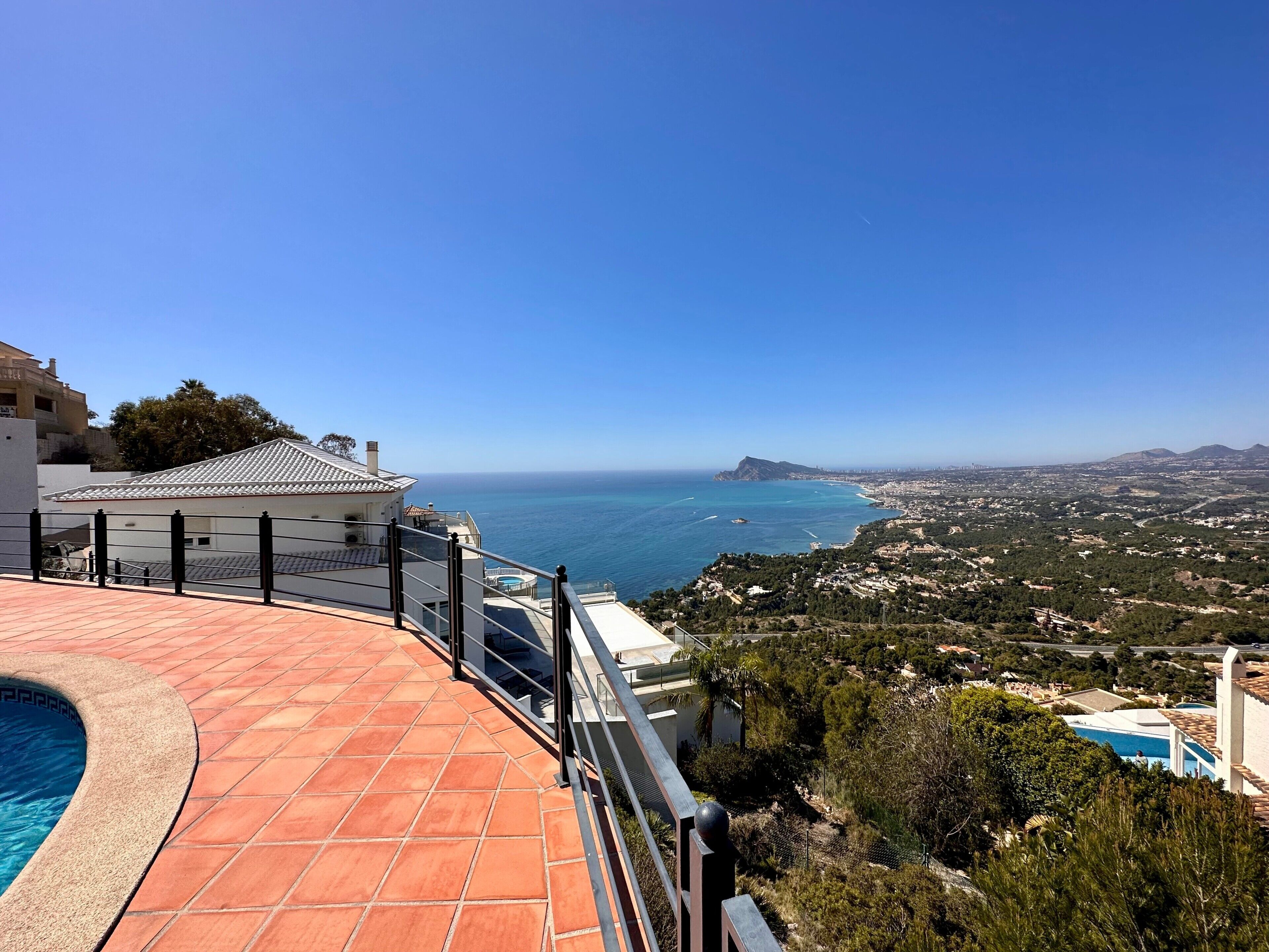 Ein Wohnhaus mit Schwimmbad, Meerblick und einem entfernten Berg.