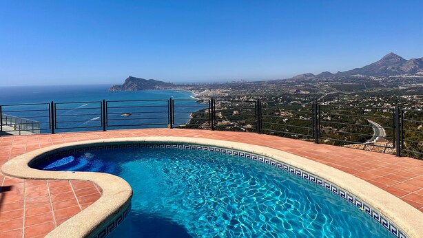 A swimming pool with a clear view of the ocean and a cityscape in the background.