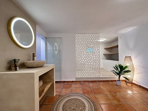 A bathroom with a round mirror, a bowl sink, a decorative panel, a potted plant, and a textured rug. - Villa 'Nono' with Amazing Sea View (Altea)