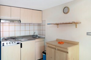 Una cocina con armarios de madera, una estufa a gas, un fregadero y un reloj en la pared.