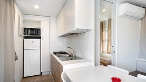 A compact kitchen with a refrigerator, stove, sink, and a dining area with a table.
