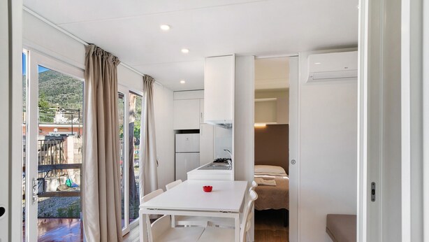 A modern interior with a dining area, kitchenette, and a bed.