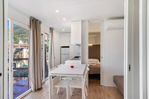 Un interior moderno con zona de comedor, kitchenette y cama.