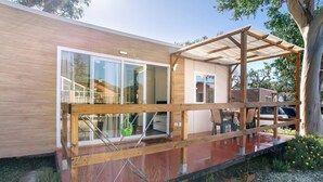 A modern house with a wooden deck, large sliding glass doors, and a covered outdoor area.