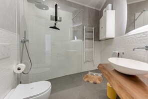 Une salle de bain moderne avec une douche à parois de verre, un lavabo blanc et un meuble-lavabo en bois.